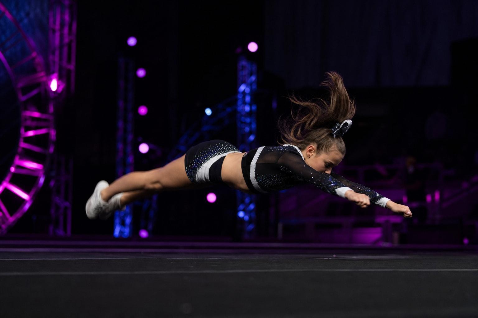 Allstar athlete mid tumbling pass on a championship stage